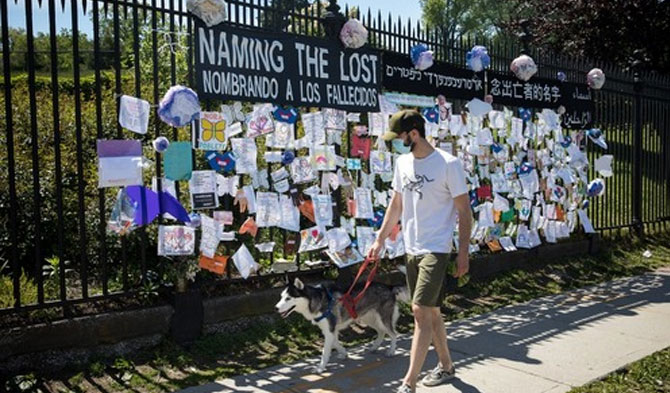 Seorang pria yang mengenakan masker berjalan melewati tanda penghormatan untuk para korban COVID-19 di depan Pemakaman Green-Wood di Wilayah Brooklyn, New York, Amerika Serikat, pada 27 Mei 2020. (Xinhua/Michael Nagle)