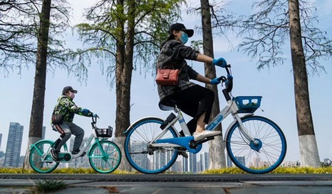 Orang-orang bersepeda di jalan jalur hijau Donghu di Wuhan, Provinsi Hubei, China tengah, pada 13 April 2020. (Xinhua/Cheng Min)