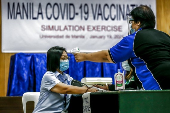 Seorang wanita yang mengenakan masker menjalani pemeriksaan suhu tubuh saat latihan simulasi vaksinasi COVID-19 di Manila, Filipina, pada 19 Januari 2021. (Xinhua/Rouelle Umali)