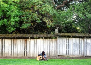 Seorang pria yang memakai masker bermain gitar di sebuah taman di San Mateo, California, Amerika Serikat, pada 17 Mei 2021. (Xinhua/Wu Xiaoling)