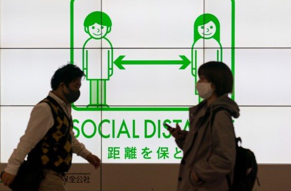 Orang-orang berjalan melewati papan pemberitahuan jaga jarak sosial (social distancing) di Tokyo, Jepang, pada 23 April 2021. (Xinhua/Christopher Jue)