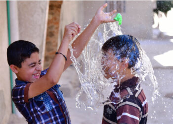 Anak-anak Suriah mendinginkan badan mereka dengan air saat cuaca panas di Damaskus, Suriah, pada 29 Juni 2021. (Xinhua)