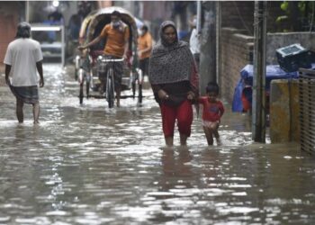 Orang-orang menerjang banjir di sebuah ruas jalan yang tergenang di daerah dataran rendah di Dhaka, ibu kota Bangladesh, pada 1 Juni 2021. (Xinhua)