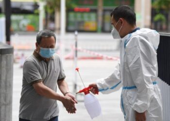 Seorang karyawan manajemen properti mendisinfeksi seorang warga yang baru saja menyelesaikan tes asam nukleat COVID-19 di Distrik Liwan di Guangzhou, Provinsi Guangdong, China selatan, pada 12 Juni 2021. (Xinhua/Deng Hua)