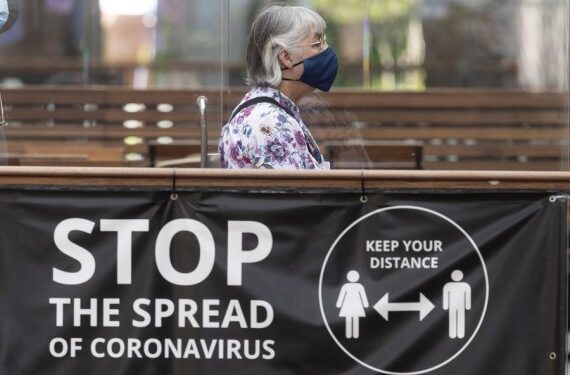 Seorang wanita yang mengenakan masker berjalan melewati spanduk berisi informasi keselamatan COVID-19 di London, Inggris, pada 19 Juli 2021. (Xinhua/Ray Tang)