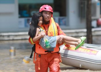 Foto yang diabadikan pada 24 Juli 2021 ini menunjukkan petugas penyelamat sedang membantu mengevakuasi seorang warga yang terjebak banjir di Baisha yang terletak di wilayah Zhongmu, Provinsi Henan, China tengah. (Xinhua/Wang Fang)