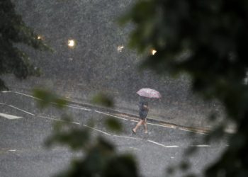 Seorang pejalan kaki berjalan di jalan yang tergenang saat hujan deras di London, Inggris, pada 25 Juli 2021. Hujan deras dan badai petir mengakibatkan banjir bandang parah di beberapa wilayah London pada Minggu (25/7), menurut media lokal. (Xinhua/Han Yan)