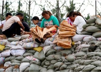Warga membuat karung pasir untuk memperkuat tanggul di wilayah Xunxian, Provinsi Henan, China tengah, pada 29 Juli 2021. (Xinhua/Li An)