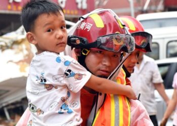 Seorang anak laki-laki dievakuasi ke tempat yang aman di Mihe, Kota Gongyi, Provinsi Henan, China tengah, pada 21 Juli 2021. (Xinhua/Li Jianan)