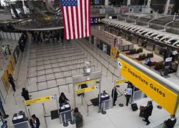 Para penumpang memasuki area pemeriksaan keamanan di Bandara Internasional John F. Kennedy di New York, Amerika Serikat, pada 13 Maret 2020.