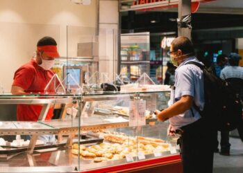 Seorang pria yang mengenakan masker membeli makanan di sebuah toko di stasiun kereta yang berlokasi di Cologne, Jerman, pada 16 Juli 2020. (Xinhua/Tang Ying)