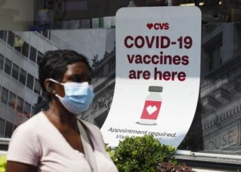 Seorang wanita berjalan melewati petunjuk informasi vaksinasi COVID-19 di sebuah apotek di New York, Amerika Serikat, pada 11 Agustus 2021.(Xinhua/Wang Ying)