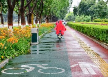 Orang-orang mengendarai sepeda di tengah hujan di sebuah jalan beraspal dengan permukaan permeabel di Kota Qian'an, Provinsi Hebei, China utara, pada 31 Juli 2021. (Xinhua/Mu Yu)