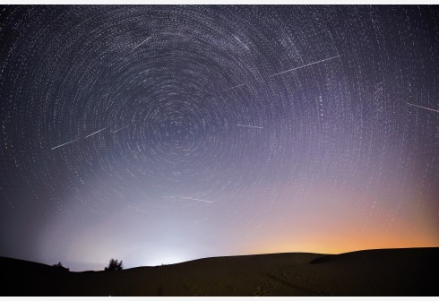 Foto montase yang diabadikan pada 13 Agustus 2021 ini menunjukkan langit malam saat Hujan Meteor Perseid di atas zona demonstrasi ekologis Engebei di Gurun Kubuqi, Daerah Otonom Mongolia Dalam, China utara. (Xinhua/Lian Zhen)