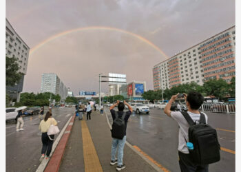 Foto yang diabadikan dengan kamera ponsel pada 26 Agustus 2021 ini menunjukkan orang-orang mengabadikan foto pelangi ganda di Beijing, ibu kota China. (Xinhua/Li Xin)
