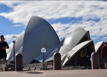 Warga berjalan dekat Gedung Opera di Sydney, Australia, Sabtu (26/6/2021). Pihak berwenang melakukan lockdown beberapa area pusat kota terbesar di Australia untuk menantisipasi penyebaran virus corona COVID-19 varian Delta yang sangat menular. (Saeed KHAN/AFP)