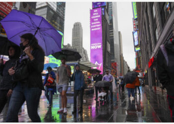 Para pejalan kaki berjalan di tengah hujan yang dipicu oleh Badai Tropis Henri di Times Square, New York, Amerika Serikat (AS), pada 22 Agustus 2021.  (Xinhua/Wang Ying)