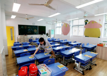 Lai Jianping membagikan buku-buku pelajaran baru di sebuah sekolah di Shanghai, China timur, pada 26 Agustus 2021. (Xinhua/Wang Xiang)