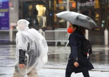 Para pejalan kaki berjalan di tengah hujan yang dipicu oleh Badai Tropis Henri di Times Square, New York, Amerika Serikat, pada 22 Agustus 2021. (Xinhua/Wang Ying)