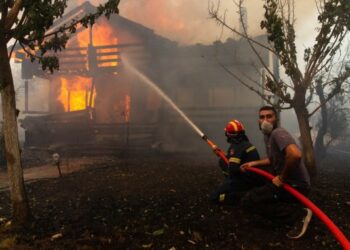 Seorang petugas pemadam kebakaran dan seorang sukarelawan berusaha memadamkan api di Afidnes, sekitar 30 kilometer dari Athena, ibu kota Yunani, pada 6 Agustus 2021. (Xinhua/Marios Lolos)