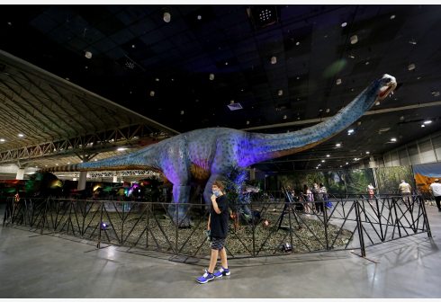 Seorang pengunjung berpose di depan sebuah model dinosaurus dalam ajang Jurassic Quest di New Orleans, Louisiana, Amerika Serikat (AS), pada 21 Agustus 2021. Ajang Jurassic Quest digelar mulai 20 hingga 22 Agustus di New Orleans, menampilkan lebih dari 100 animatronik dinosaurus berukuran sebenarnya. (Xinhua/Lan Wei)