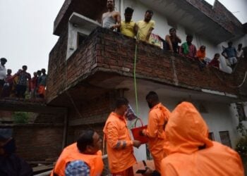 Anggota Pasukan Tanggap Bencana Nasional (National Disaster Response Force/NDRF) mendistribusikan bantuan kepada warga yang terdampak banjir di Distrik Prayagraj, Negara Bagian Uttar Pradesh, India utara, pada 11 Agustus 2021. (Xinhua/Str)