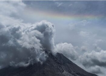 Foto yang diabadikan pada 9 Agustus 2021 ini menunjukkan pelangi di cakrawala saat Gunung Sinabung memuntahkan asap dan material vulkanik seperti yang terlihat dari Desa Gamber di Karo, Sumatra Utara. (Xinhua/Sutanta Aditya)