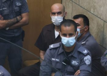 Ayham Kamamji, salah satu dari enam tahanan yang melarikan diri dari penjara Gilboa di Israel beberapa pekan lalu, dikelilingi oleh aparat kepolisian Israel di ruang pengadilan di Kota Nazaret, Israel utara, pada 19 September 2021. (Xinhua/JINI/David Cohen)
