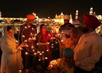 Para penganut Sikh menyalakan lampu di Kuil Emas, tempat tersuci dalam agama Sikh, dalam rangka peringatan 417 tahun edisi pertama Sri Guru Granth Sahib di Amritsar pada 7 September 2021. (Xinhua/Stringer)