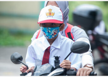 Seorang siswa sekolah dasar yang memakai masker dijemput di sekolah dengan sepeda motor oleh orang tuanya di Tangerang Selatan, Provinsi Banten, pada 13 September 2021. Jumlah kasus COVID-19 di Indonesia naik 2.577 dalam satu hari menjadi 4.170.088, dengan jumlah kematian bertambah 276 menjadi 139.165, kata Kementerian Kesehatan pada Senin (13/9). (Xinhua/Veri Sanovri)