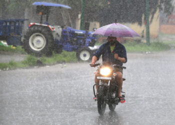 Seorang pria mengendarai sepeda motor di tengah hujan lebat di Distrik Amritsar di Negara Bagian Punjab, India utara, pada 8 September 2021. (Xinhua/Str)