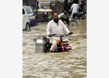 Seorang pria mengendarai sepeda motor melewati jalan yang tergenang banjir pascahujan deras di kota pelabuhan Karachi, Pakistan selatan, pada 23 September 2021. (Xinhua/Str)