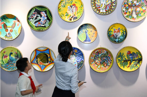 Seorang guru dan siswa mengamati berbagai karya seni yang ditampilkan pada Pekan Kerja sama Pendidikan China-ASEAN 2019 di Guiyang, ibu kota Provinsi Guizhou, China barat daya, pada 22 Juli 2019. (Xinhua/Yang Wenbin)