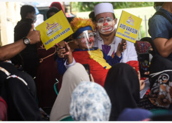 Anggota komunitas badut memegang plakat bertuliskan slogan pencegahan dan pengendalian epidemi di tengah kampanye vaksinasi COVID-19 di Tangerang, Provinsi Banten, pada 14 September 2021. (Xinhua/Agung Kuncahya B.)