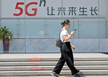 Seorang wanita berjalan melewati papan iklan jaringan 5G di Beijing, ibu kota China, pada 3 Juni 2019. (Xinhua/Cai Yang)