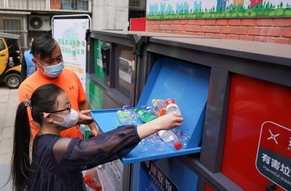Seorang anak memasukkan botol plastik ke dalam tempat sampah cerdas berwarna biru di lingkungan permukiman Shaojiu di Distrik Dongcheng, Beijing, ibu kota China, pada 17 Mei 2020. (Xinhua/Ju Huanzong)