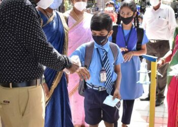 Seorang guru memeriksa suhu tubuh para siswa setibanya mereka di sebuah sekolah dasar di Bangalore, India, pada 6 September 2021. (Xinhua/Str)