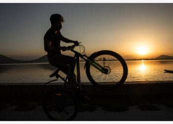 Seorang anak laki-laki mengendarai sepedanya di tepi Danau Dal saat matahari terbenam di Kota Srinagar, ibu kota musim panas Kashmir yang dikuasai India, pada 6 Oktober 2021. (Xinhua/Javed Dar)