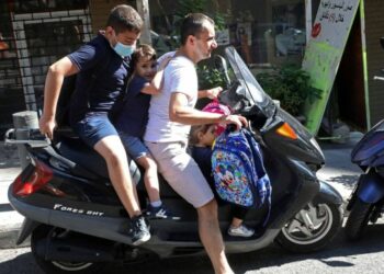 Seorang pria Lebanon mengantarkan tiga orang anak ke sekolah dengan mengendarai sepeda motor listrik di Beirut, Lebanon, pada 21 Oktober 2021. (Xinhua/Bilal Jawich)