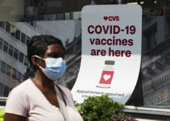 Seorang wanita berjalan melewati poster vaksinasi COVID-19 di sebuah apotek di New York, Amerika Serikat, pada 11 Agustus 2021. (Xinhua/Wang Ying)
