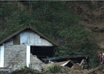 Seorang pria berjalan di dekat sebuah rumah yang rusak pascagempa magnitudo 4,8 dan tanah longsor melanda Bali pada 16 Oktober 2021. (Xinhua/Komang Alfan)