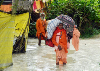 Orang-orang yang membawa barang-barang mereka berjalan melintasi sebuah area yang tergenang air di sepanjang tepi Sungai Gangga di Kota Haridwar, Negara Bagian Uttarakhand, India utara, pada 19 Oktober 2021. Korban tewas di Negara Bagian Uttarakhand yang dilanda banjir bertambah menjadi 34 orang, kata kepala menteri negara bagian itu, Pushkar Singh Dhami, pada Selasa (19/10) setelah melakukan survei dari udara di daerah-daerah yang terdampak banjir. (Xinhua/Str)