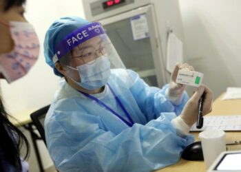 Seorang tenaga kesehatan menunjukkan informasi yang tertera pada kotak vaksin COVID-19 di sebuah pusat kesehatan masyarakat di Jiading, Shanghai, pada 19 April 2021. (Xinhua/Liu Ying)