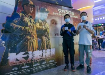 Dua anak laki-laki berpose di depan papan poster "The Battle at Lake Changjin" di sebuah bioskop di Kunming, Provinsi Yunnan, China barat daya, pada 1 Oktober 2021. (Xinhua/Chen Xinbo)