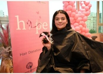 Seorang gadis menunjukkan rambutnya dalam acara donasi rambut di Kegubernuran Hawalli, Kuwait, pada 19 Oktober 2021. Rambut yang disumbangkan tersebut akan dibuat menjadi wig untuk pasien kanker yang menjalani kemoterapi. (Xinhua/Asad)