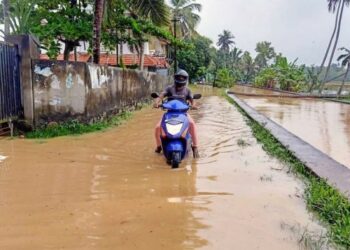 Seorang warga melintasi jalan yang tergenang air dengan sepeda motor di Thiruvananthapuram, Kerala, India, pada 16 Oktober 2021. (Xinhua)