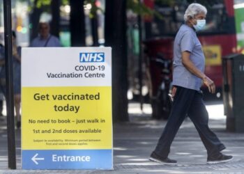 Seorang pria berjalan melewati sebuah pusat vaksinasi COVID-19 NHS di London, Inggris, pada 7 September 2021. (Xinhua/Ray Tang)