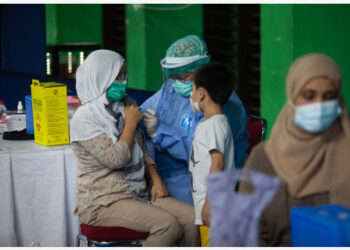 Seorang tenaga kesehatan menyuntikkan dosis vaksin COVID-19 kepada seorang wanita dalam program vaksinasi bagi para pengungsi dan pencari suaka di Jakarta pada 7 Oktober 2021. (Xinhua/Edy Susanto)