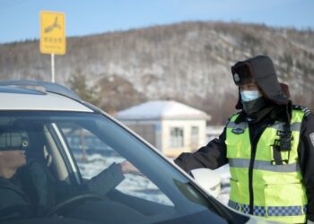 Polisi lalu lintas bernama Sun Chen memeriksa surat izin mengemudi (SIM) di sebuah jalan di Distrik Huzhong di Dahinggan, Provinsi Heilongjiang, China timur laut, pada 8 Januari 2021. (Xinhua/Wang Jianwei)