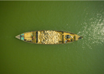 Foto dari udara yang diabadikan pada 24 Oktober 2021 ini menunjukkan sebuah perahu yang mengangkut bebatuan di Sungai Jadukata di Sunamganj, Bangladesh. (Xinhua)
